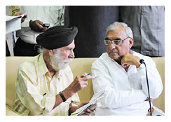 मुख्यमंत्री हुड्डा के बिलकुल बगल में बैठकर उन्हें समझाते पत्रकार एसएन परवाना