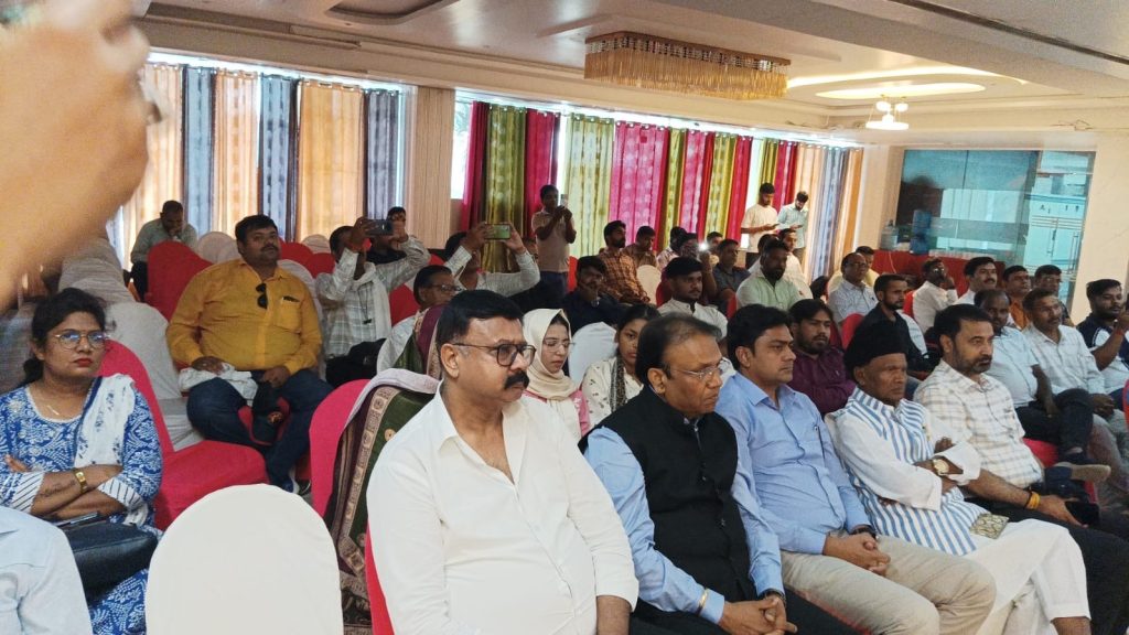 10bcc93b-4d7f-4848-ad53-25a262428ed7 | No. 1 Indian Media News Portal Audience seated in a hall for a conference, with colorful curtains in the background and a few attendees standing to take photos.
