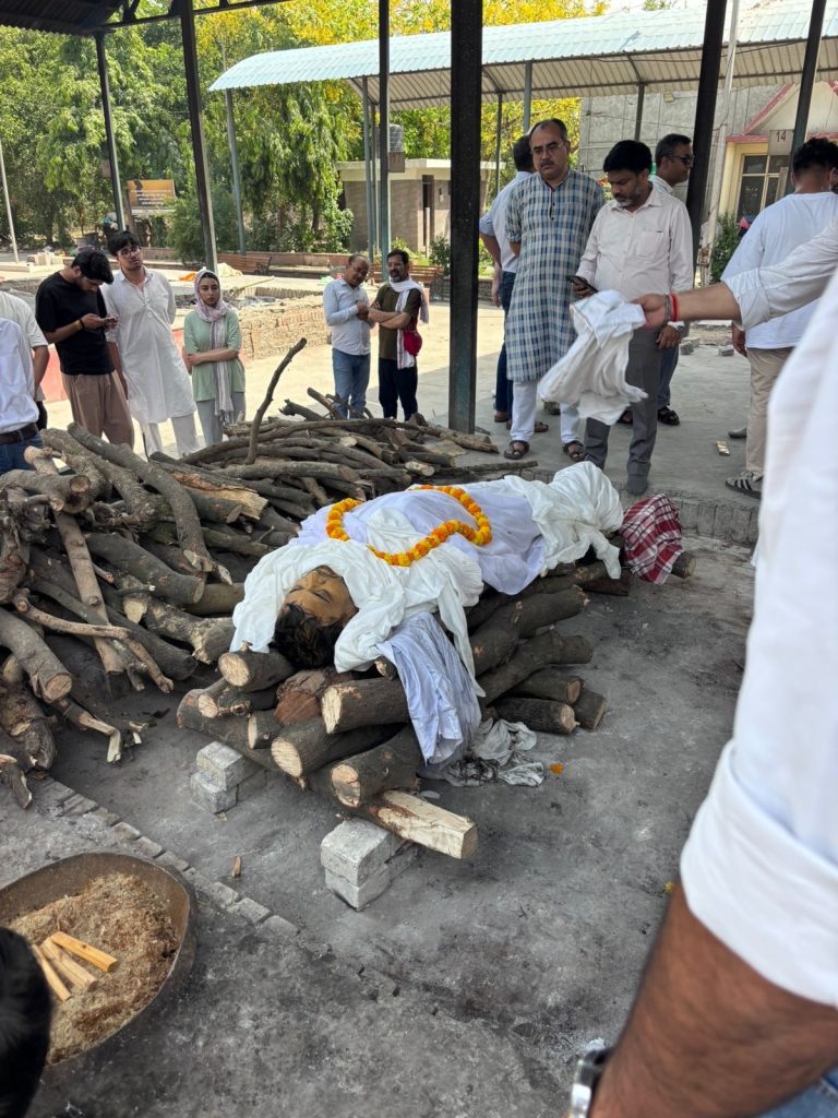 345c1a61-5406-4362-ba69-096f8cfe5763 | No. 1 Indian Media News Portal Mourners stand around a funeral pyre of stacked wooden logs with a body wrapped in white cloth and garland prepared for cremation