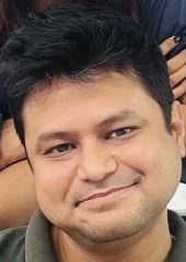 Close-up of a man with short dark hair smiling at the camera.