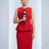 Female news presenter in a red sleeveless dress holding a microphone labeled 18 in a studio.