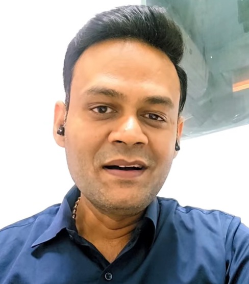 asish sinha | No. 1 Indian Media News Portal Portrait of a man taking a selfie, wearing a dark blue shirt and wireless earbuds, looking at the camera.