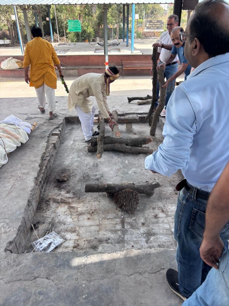 b2794eea-113d-4ad8-a77a-b0d1e286ff75 | No. 1 Indian Media News Portal Men working together to clear a rectangular pit, lifting logs and placing debris in a public outdoor area.