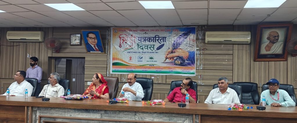 ghazipur samman_1 | No. 1 Indian Media News Portal Panel of seven people seated at a long conference table in a meeting room, with a colorful banner behind them and portraits on the wall.