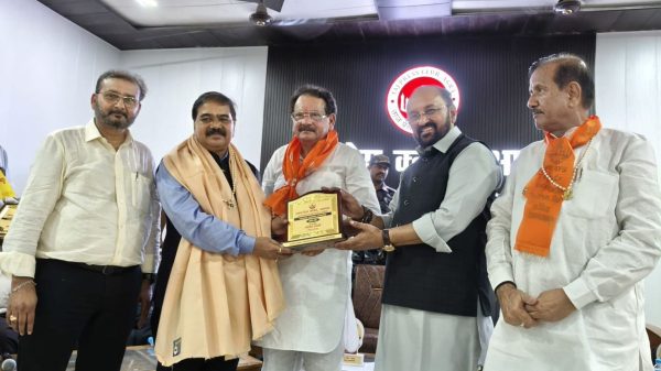 Group of men at an award ceremony exchanging a plaque on stage.