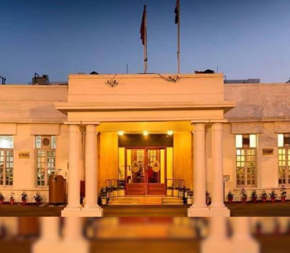 Front entrance of a neoclassical building with four white columns and warm exterior lighting at dusk
