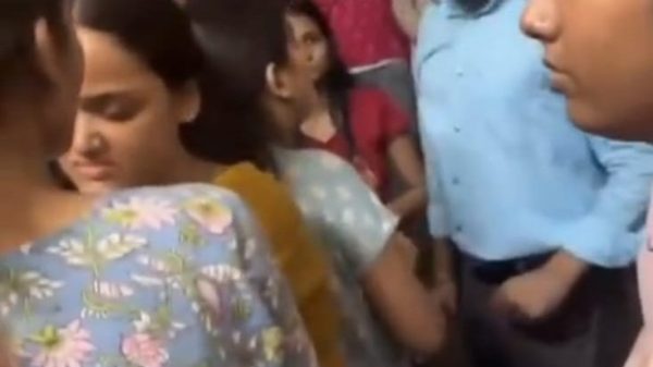 Crowded group of women in colorful clothing with Hindi text overlay about university faculty and student suicide.