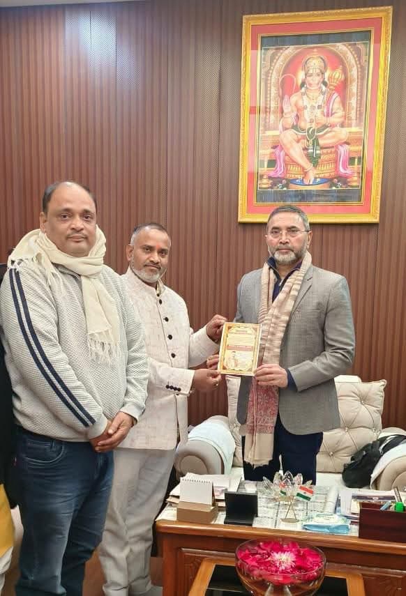 img_8274 | No. 1 Indian Media News Portal Three men in a formal office exchange a certificate, with a framed deity painting on the wall behind them.