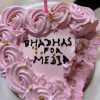 Pink frosted cake with many rose-like swirls and gold beads, a single pink candle, and a bite taken from the side; message partially visible on the cake surface.