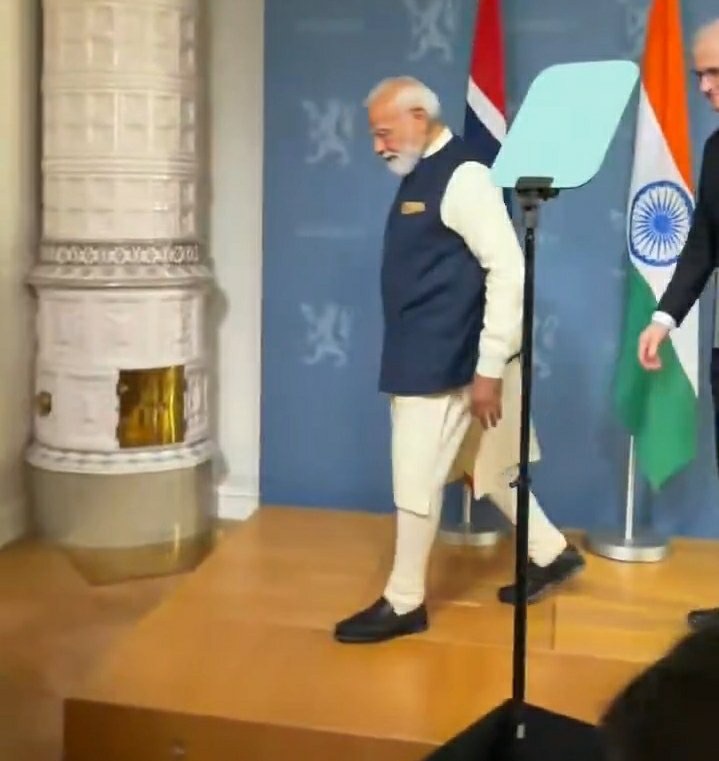 img_8364 | No. 1 Indian Media News Portal Prime Minister Narendra Modi walking off a stage in a white kurta and navy vest, with the Indian flag in the background.