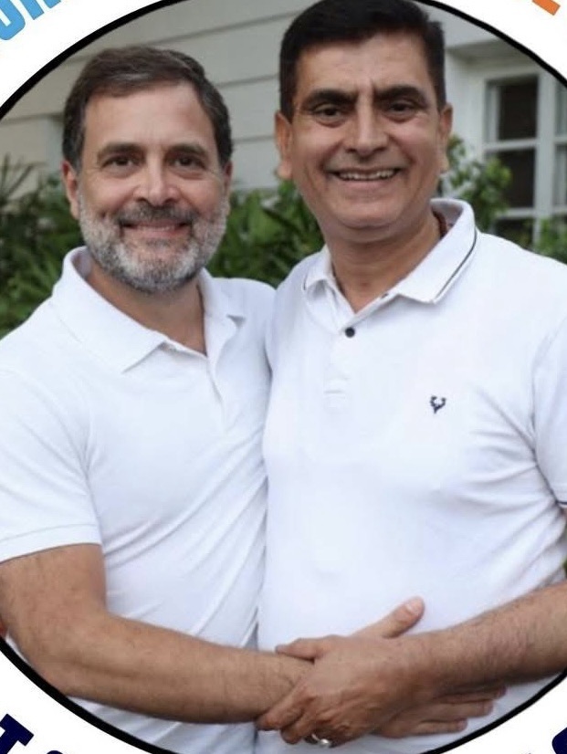 Two men in white polo shirts smiling at the camera while shaking hands outdoors.