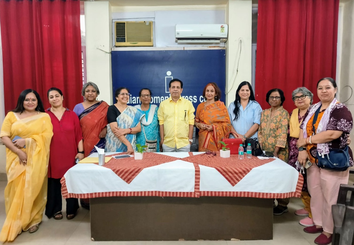 A diverse group of ten people standing behind a long table covered with a white and red cloth in a conference room, posing for a group photo.