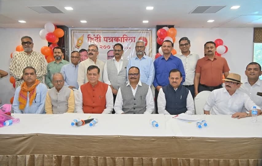 kpc | No. 1 Indian Media News Portal Group of fifteen men posing for a photo at a press event in a room with balloons and a banner in the background; water bottles on the table.