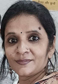 Close-up portrait of a South Asian woman with a bindi, nose ring, and earrings, looking at the camera.