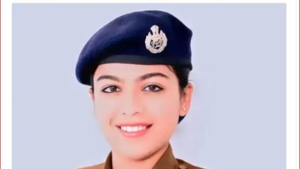 Portrait of a smiling female police officer in a brown uniform and blue beret, head-and-shoulders shot.
