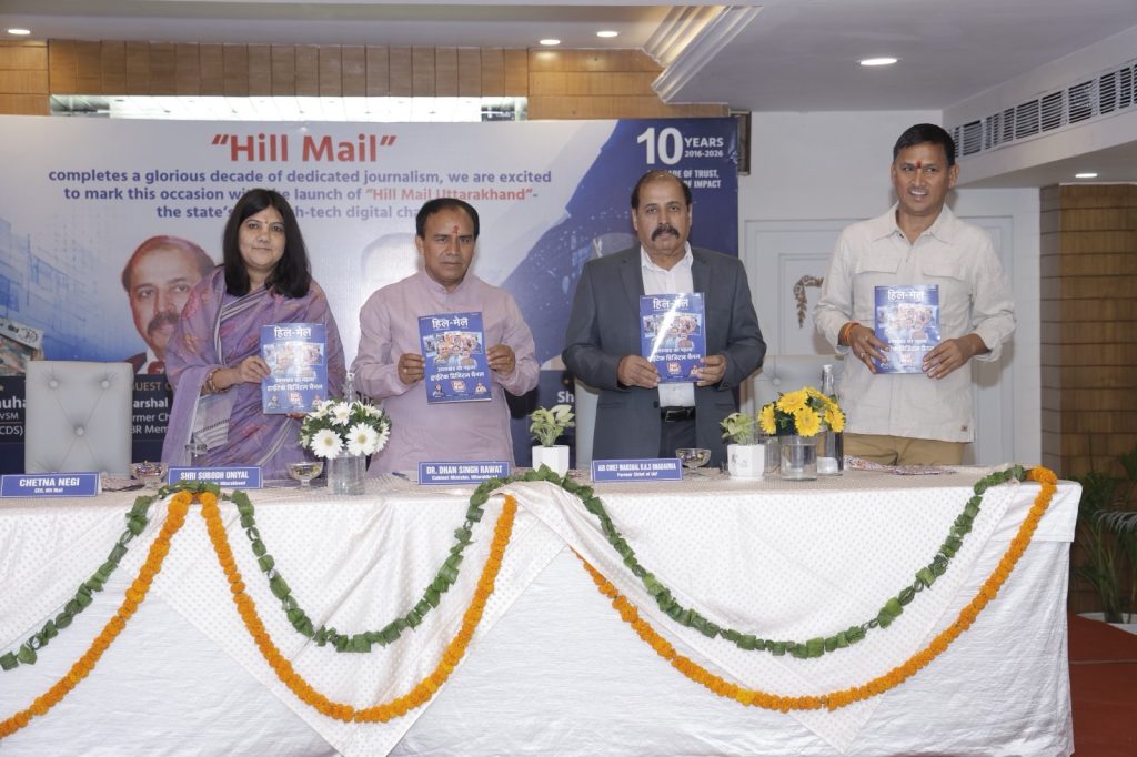 ba294234-9fe5-43b1-9946-b2dcea58210b | No. 1 Indian Media News Portal Panel of four people at a booking launch event holding blue booklets, in front of a 'Hill Mail' banner announcing 10 years.