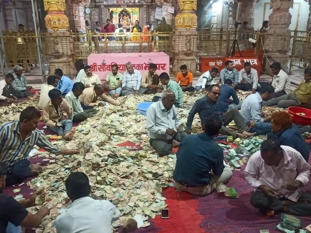 chanda | No. 1 Indian Media News Portal Group of men sitting on a red carpet inside a temple, sorting and counting large piles of cash.
