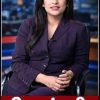 TV news anchor seated in a studio wearing a purple suit, with a red lower-third banner showing white Hindi text.