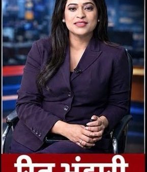 TV news anchor seated in a studio wearing a purple suit, with a red lower-third banner showing white Hindi text.