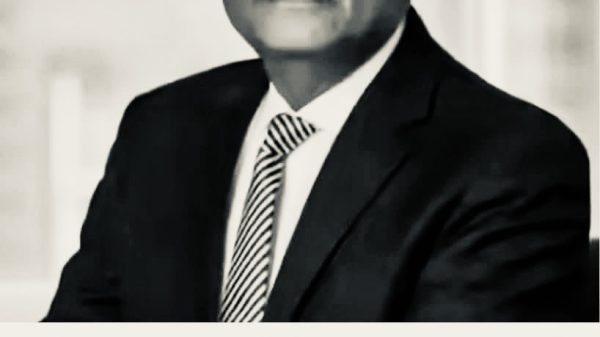 Portrait of a man in a suit and glasses, paired with a Hindi news headline about ED raids on a prominent figure or location.