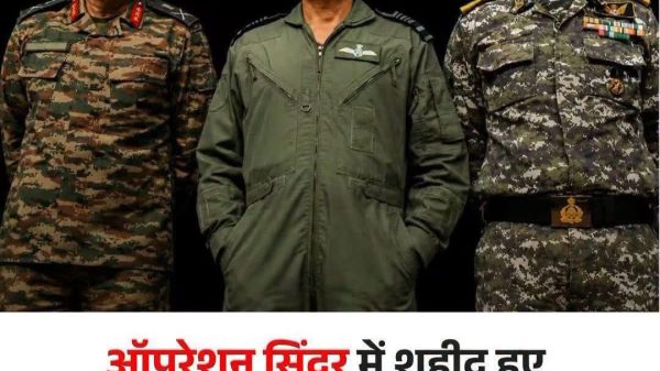 Three military officers in camouflage and green flight suits stand side by side on a dark stage, with a bold Hindi headline below. The headline reads: 'ऑपरेशन सिंदूर में शहीद हुए 6 भारतीय सैनिकों के नाम पहली बार सार्वजनिक, सरकार ने बताई पहचान'.