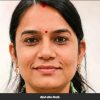 Close-up portrait of a smiling woman with a red bindi, wearing gold earrings.