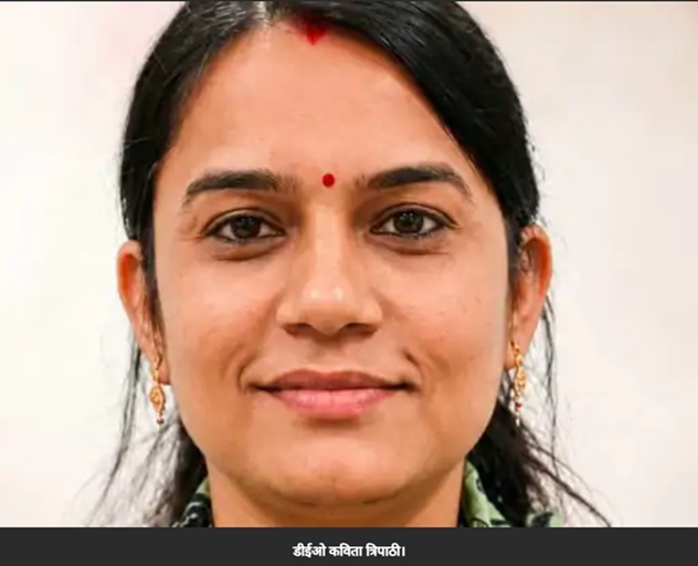 Close-up portrait of a smiling woman with a red bindi, wearing gold earrings.