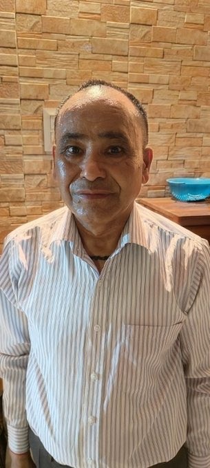 keshav negi | No. 1 Indian Media News Portal Smiling middle-aged man with short hair, wearing a light blue striped button-down shirt, indoors in front of a tan brick wall; a blue bowl sits on a counter behind him.