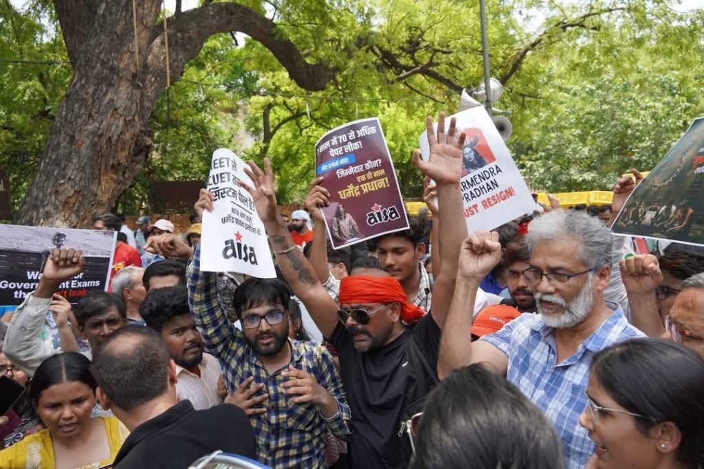 left party | No. 1 Indian Media News Portal A large crowd of protesters outdoors, many raising their fists and signs; signs include 'AISA' logos and text in Hindi, with green trees in the background.