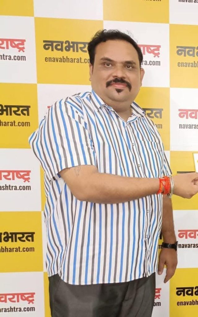 manoj pandey | No. 1 Indian Media News Portal Man in a blue-and-white striped shirt posing for a photo against a yellow-and-white Navbharat backdrop with logos.