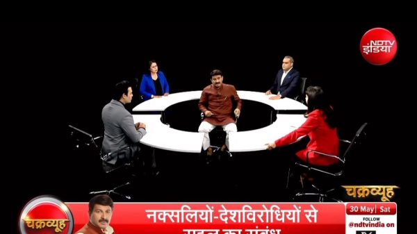 Six-panel debate around a circular white table in a dark studio; NDTV India logo visible, red banner with Hindi text at the bottom.