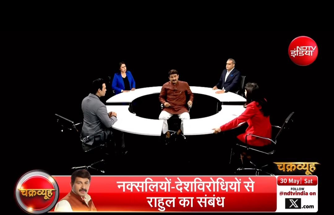 Six-panel debate around a circular white table in a dark studio; NDTV India logo visible, red banner with Hindi text at the bottom.