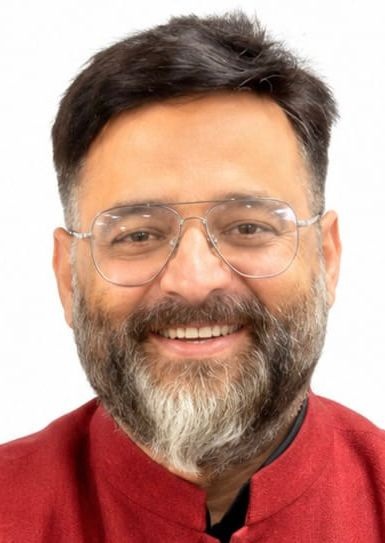 praveen tiwari | No. 1 Indian Media News Portal Smiling man with short dark hair, gray beard and clear glasses, wearing a red shirt.