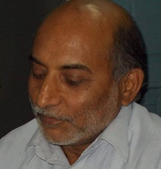 Portrait of a middle-aged man with a gray beard, looking down.