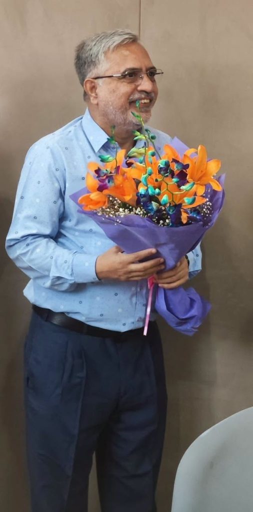 priyadarshan_pd | No. 1 Indian Media News Portal Smiling man in a light blue shirt holds a large bouquet of orange and blue flowers wrapped in purple paper.