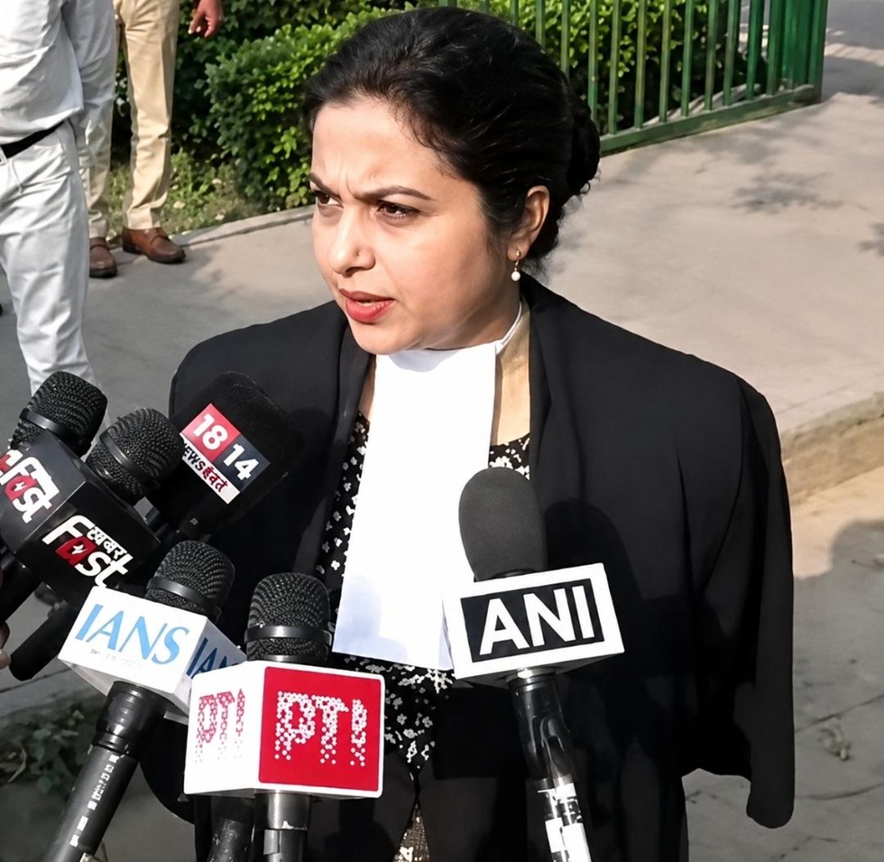 Woman in a black blazer speaks to reporters, surrounded by multiple microphones labeled ANI, IANS, PTI and others.