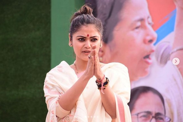 Young Indian woman in a white sari with hands pressed together in a namaste gesture outdoors