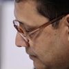 Close-up side profile of a man wearing brown-rimmed glasses looking downward.