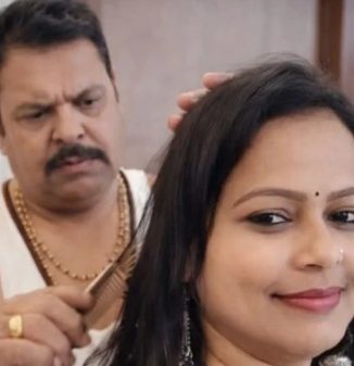 Man with a mustache behind a woman, grooming or combing her hair as she smiles softly.