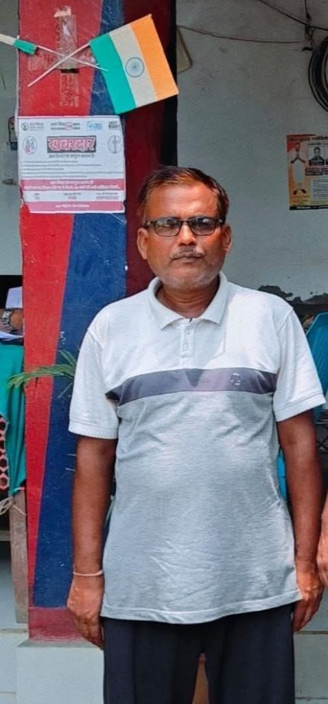 vijay gupta | No. 1 Indian Media News Portal Middle-aged man with glasses standing indoors in front of a red-and-blue pillar and an Indian flag overhead.