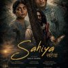 Poster for the film Sahiya: a woman and a man huddle behind a tree as armed soldiers advance around them, conveying danger and wartime tension. Tagline reads: 'To live together they must survive together.'