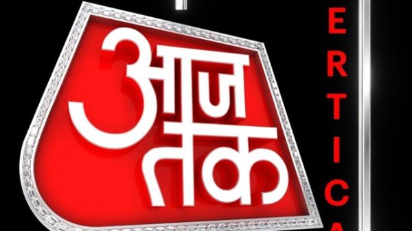 Logo for Aaj Tak news channel featuring a red diamond-shaped badge with white Hindi text on a black background and 'Vertical' written vertically on the right.