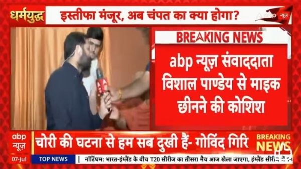 ABP News breaking screen with two men on a stage; one holds a microphone as a presenter interview unfolds, red breaking-news banner in Hindi visible.
