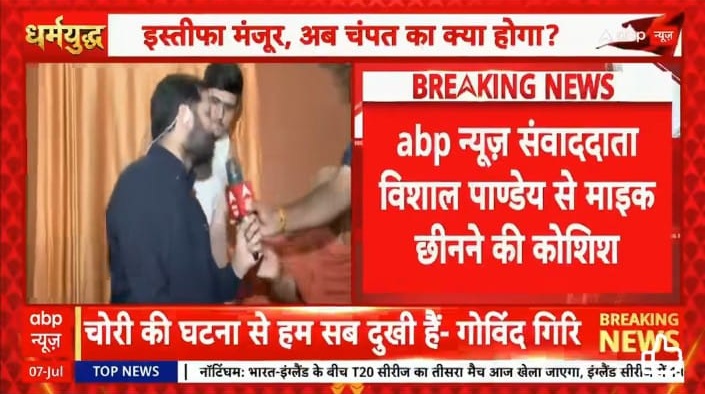 ABP News breaking screen with two men on a stage; one holds a microphone as a presenter interview unfolds, red breaking-news banner in Hindi visible.