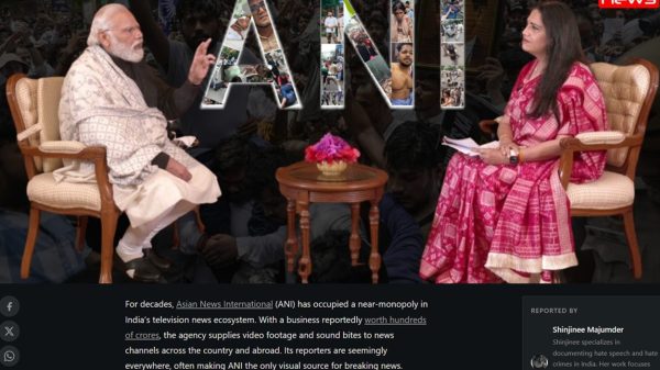 Two people sit facing each other in an interview setup, with a small table and pink flower, a large ANI collage in the background, and a news logo top-right.