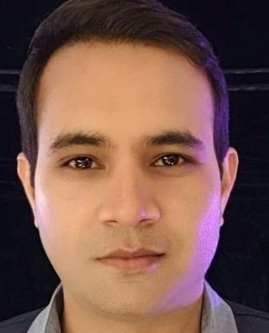 Close-up portrait of a man with short dark hair and a neutral expression, facing the camera.