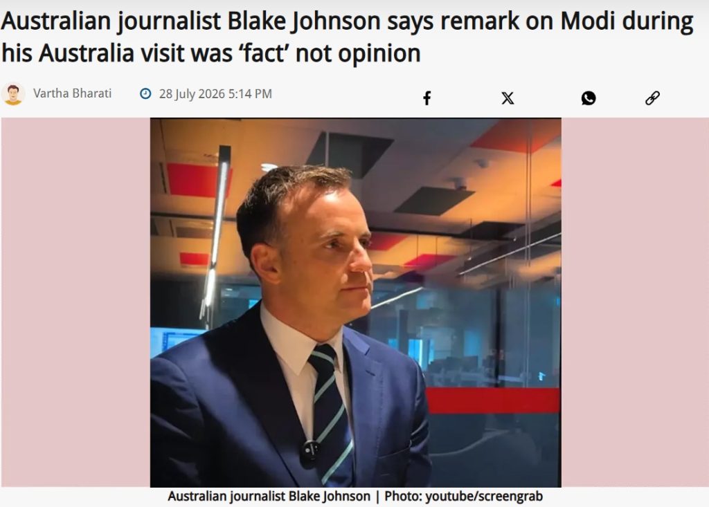 Australian journalist Blake Johnson in a navy suit and striped tie, in a newsroom backdrop.