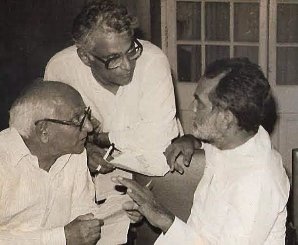 chandrashekhar | No. 1 Indian Media News Portal Three men in white shirts huddle over a document, discussing in what appears to be a small office.