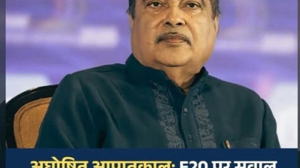 Portrait of a middle-aged man with a mustache wearing a dark green kurta, seated, with a blue-purple news banner at the bottom containing Hindi text about E20, FIRs, and Nagpur police action (informational image).