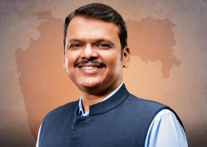 Smiling man in a blue Nehru jacket against an orange map of India backdrop.